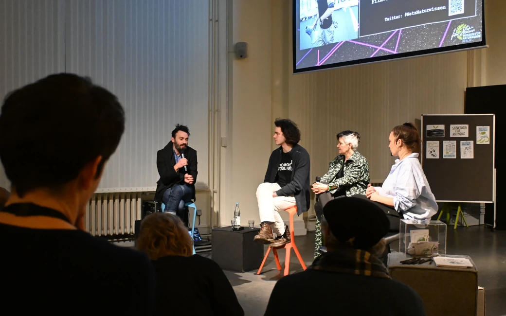Vier Menschen sitzen auf Stühlen und diskutieren miteinander.