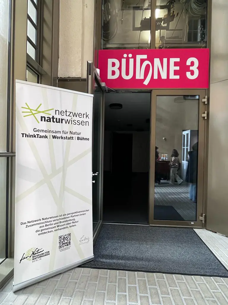 Der Eingang zum Saal “Bühne 3” des Theaters an der Parkaue wird gezeigt. Am Rand steht ein Text-Banner des Projektes Netzwerk Naturwissen.