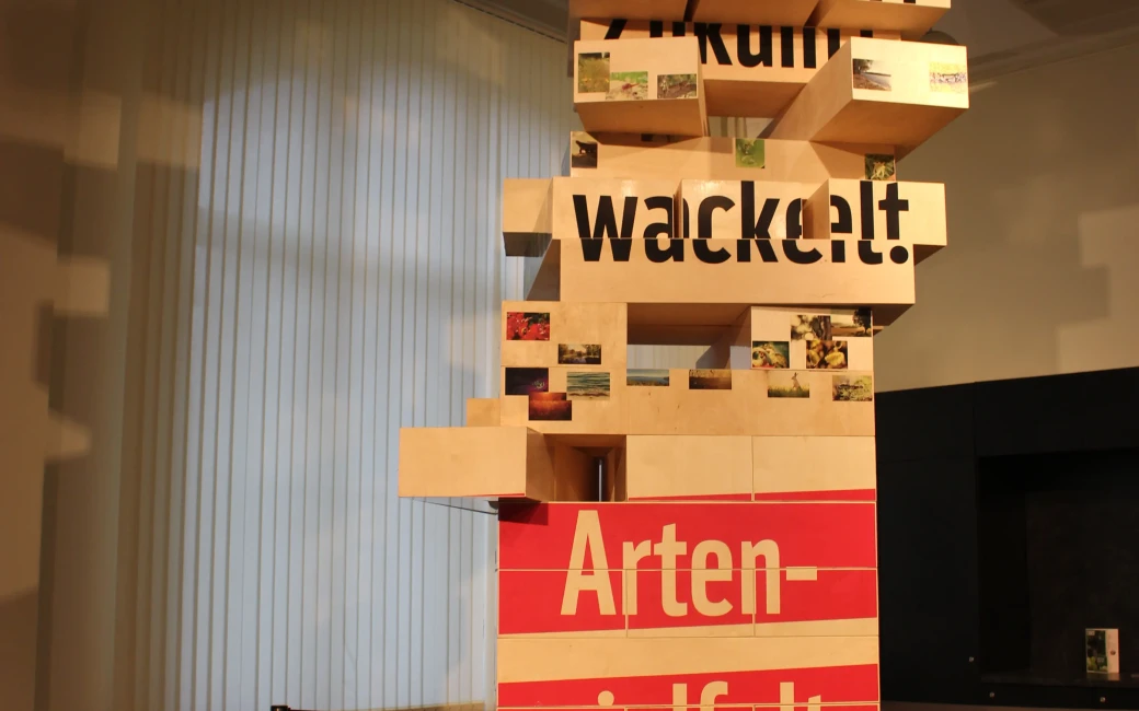 Der Turm steht im Museum für Naturkunde Berlin. Er ist schief und einzelne Holzstücke fehlen bereits bzw. sind am Rausrutschen.