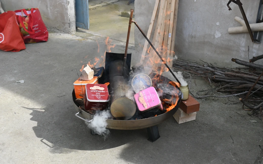 Feuerschale mit Metallboxen im Feuer beim Köhler-Prozess