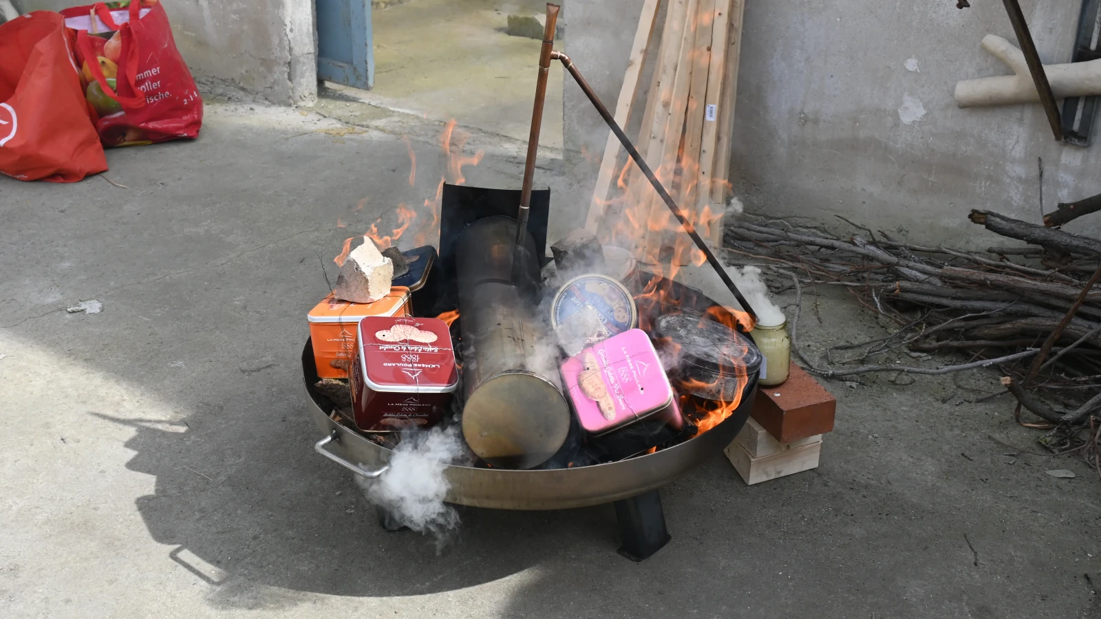 Feuerschale mit Metallboxen im Feuer beim Köhler-Prozess