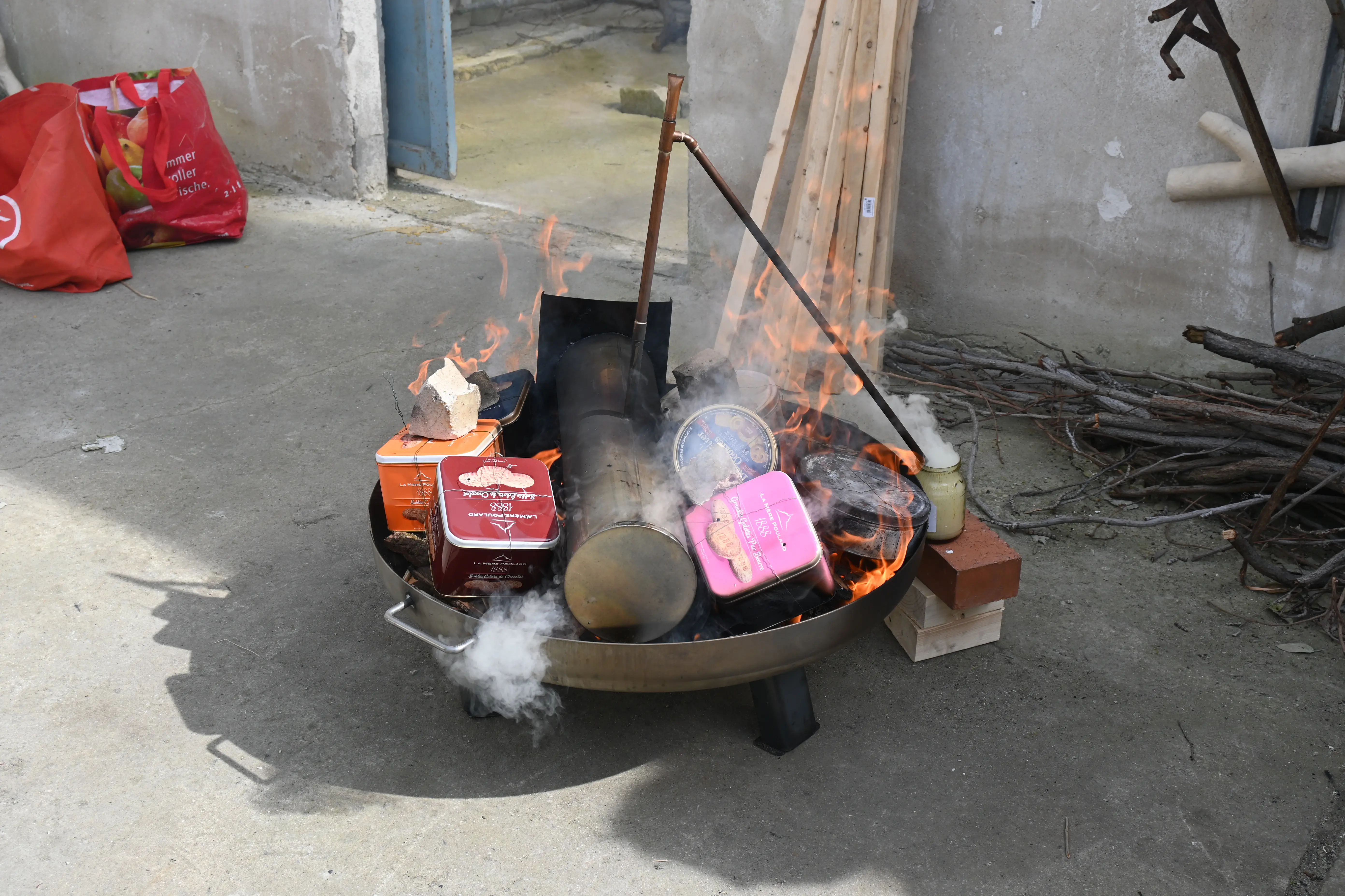 Feuerschale mit Metallboxen im Feuer beim Köhler-Prozess